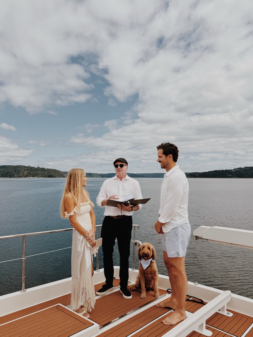 The ceremony on the back deck of the boat, the officiant reading, the dog sitting between them
