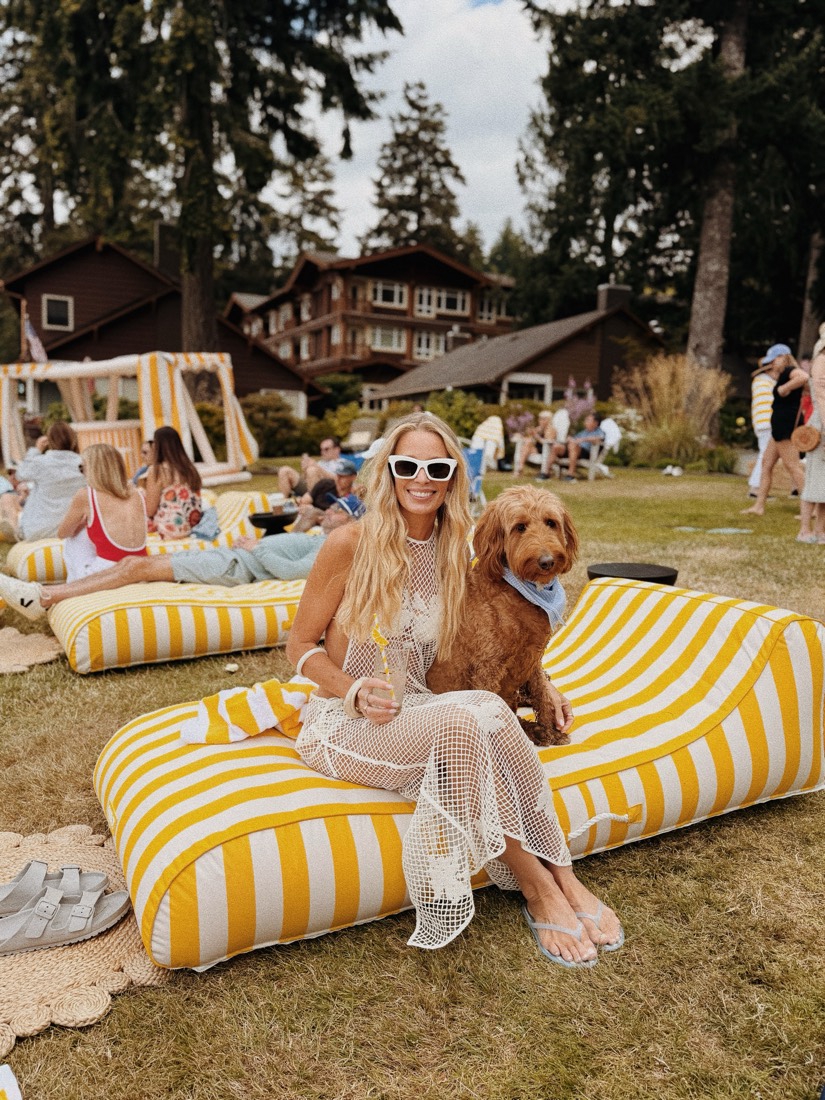 Katie on a yellow striped lounger on the lawn with a golden retriever