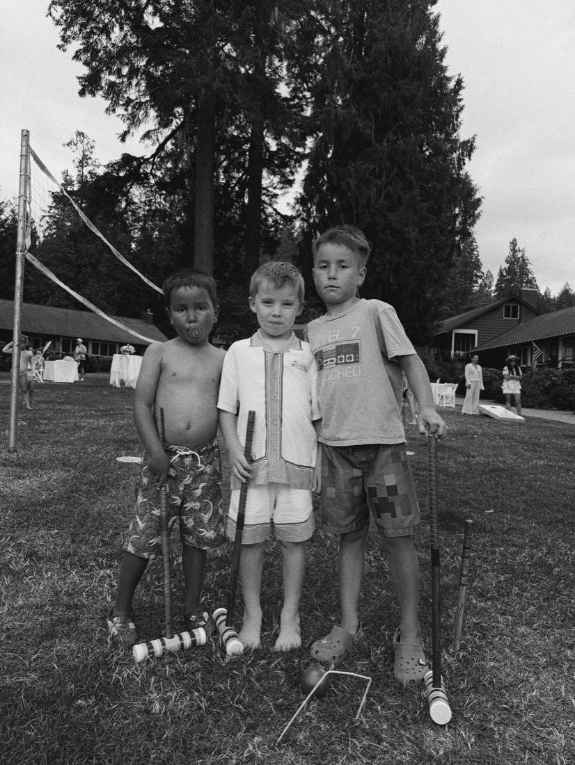 Three children holding croquet mallets on the lawn