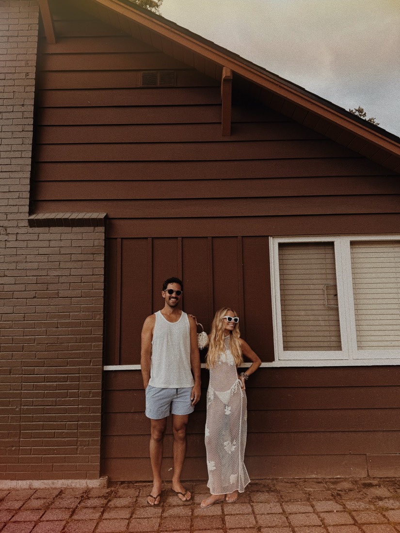Katie and Danny in front of the brown boards of the resort building